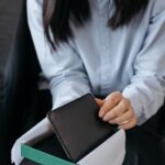 ギフトボックスに入った黒い革財布を開ける女性