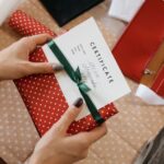 赤い包装の贈り物にメッセージカードを添える手元