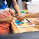 テーブルで木製パズルに取り組む子どもと大人の手元