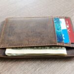 木の板の上に置いた紙幣とカードを収めた薄型のスリム財布