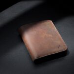 黒い背景に立てた茶色い本革の縦型財布