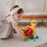布製のあひるのおもちゃを持って遊ぶ幼児