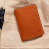 布に包まれたギフトボックスの上に置かれた茶色い革のカードケース型財布