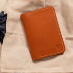 布に包まれたギフトボックスの上に置かれた茶色い革のカードケース型財布