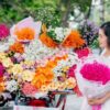 大きな花束を店先で受け取る女性