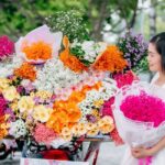 大きな花束を店先で受け取る女性