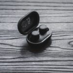 木目の台に置かれた黒いワイヤレスイヤホンのケース