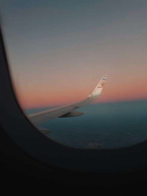 機内の窓から見える飛行機の翼と夕暮れの空