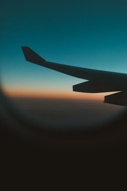 飛行機の翼と青からオレンジへ変わる空のグラデーション