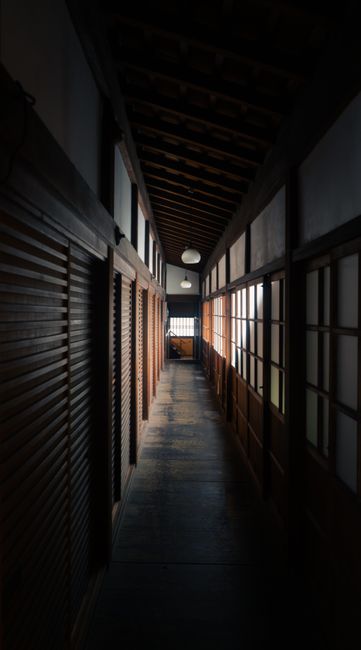 日本の伝統的な木造建築が並ぶ薄暗い路地