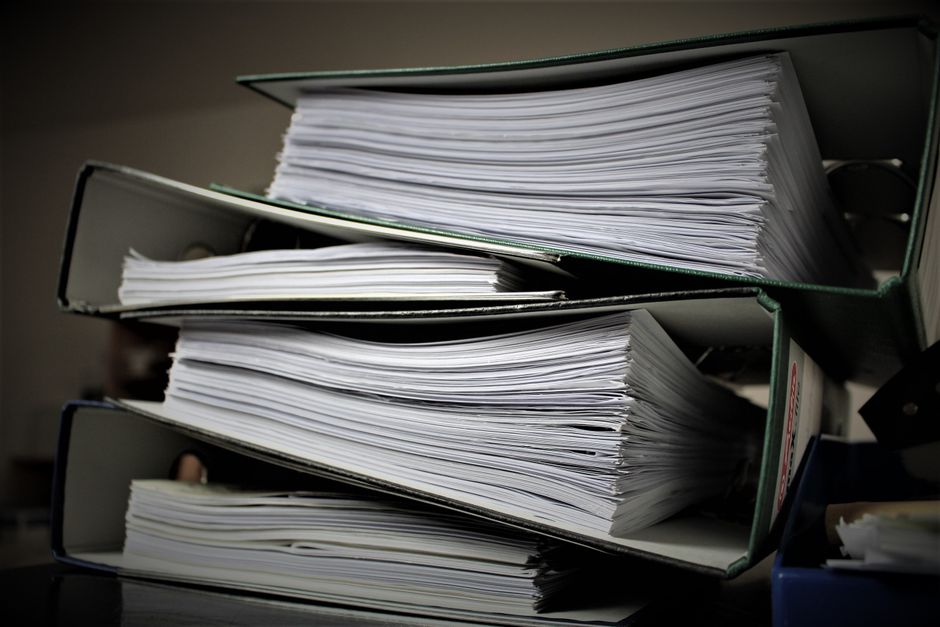 棚に積み重ねられた複数のリングバインダーと書類