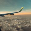 飛行機の翼越しに見える夕焼けと雲海