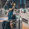 新幹線ホームでスーツケースを持って電車を待つ旅行者