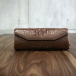 木のテーブルに置いたクロコ型押しの茶色い革財布