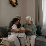 クリスマスツリーのあるリビングで孫と一緒にプレゼントを開ける祖父母