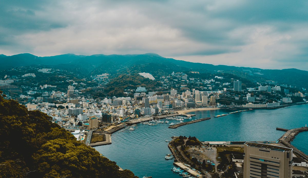 静岡県熱海市の海沿いの街並みと港を山の上から見渡した風景