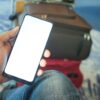 空港で旅行用バッグの上にスマートフォンを持つ手元